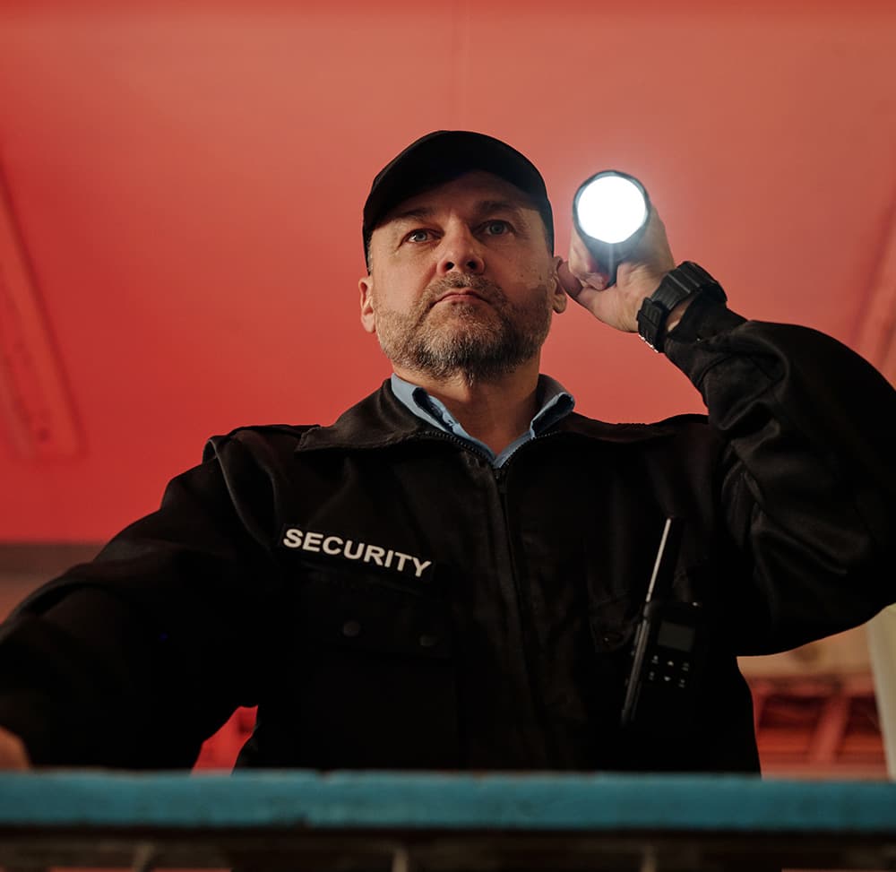 Sicherheitskraft mit Taschenlampe bei der Kontrolle
